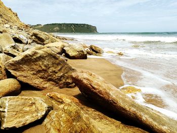 Scenic view of rocks on beach against sky