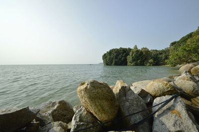 Rocks by sea against clear sky