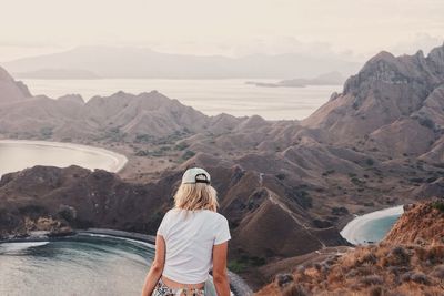 Rear view of woman standing on mountain against sky