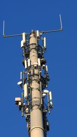 Low angle view of communications tower against clear blue sky