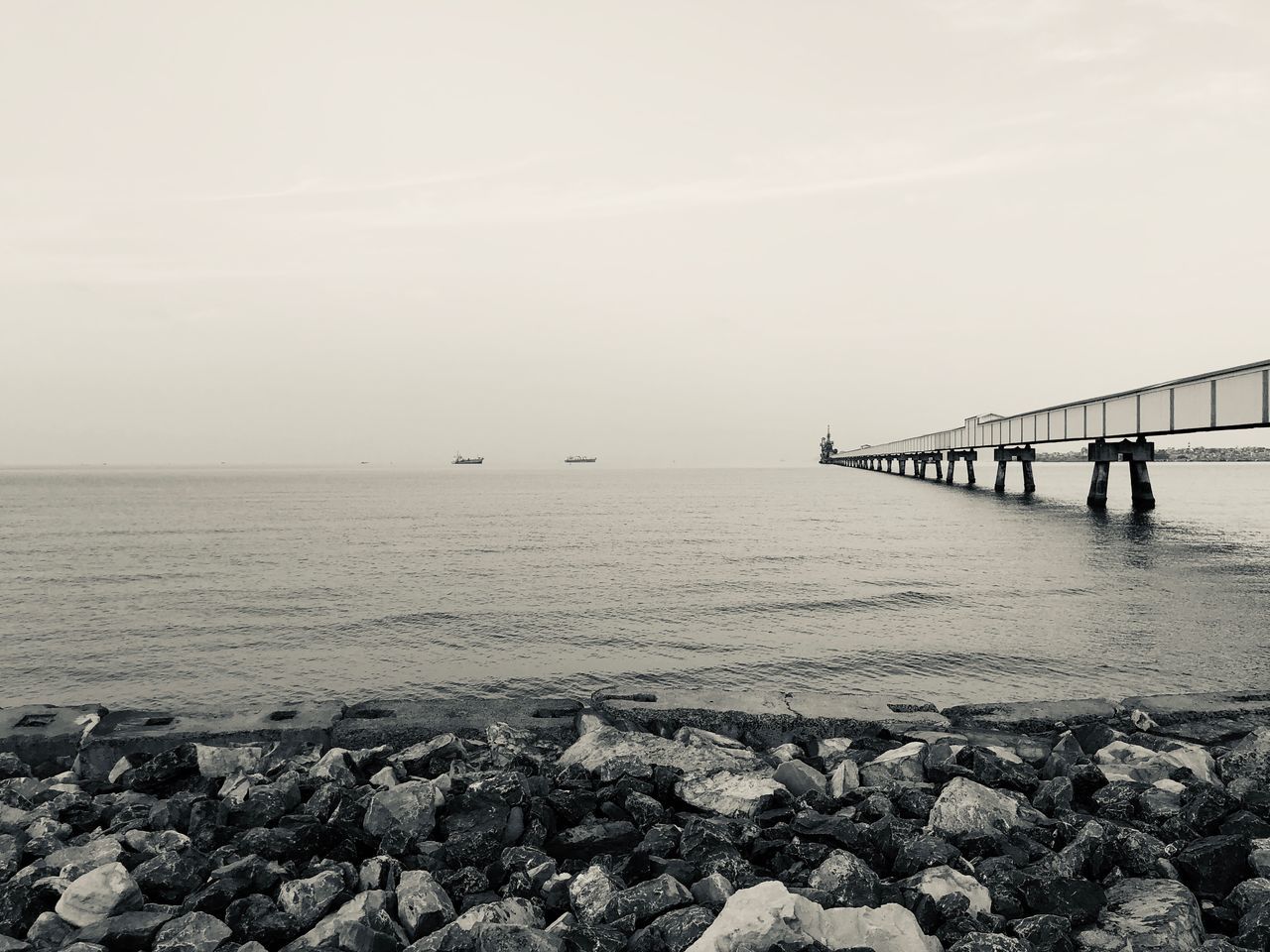 water, sea, sky, rock, scenics - nature, horizon, beauty in nature, horizon over water, built structure, solid, rock - object, tranquil scene, nature, architecture, tranquility, day, pier, beach, bridge, outdoors, bridge - man made structure, no people, architectural column, pebble