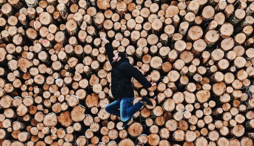 Side view of mid adult man jumping against logs