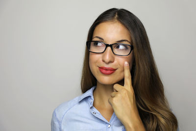 Close-up of woman wearing eyeglasses against gray background