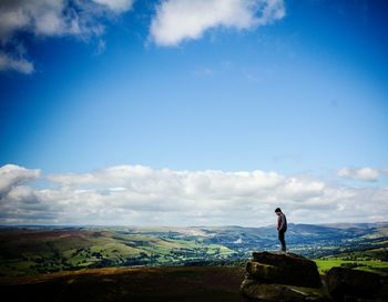 Hiker standing on rock against sky