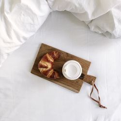 High angle view of coffee and croissant on bed