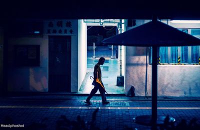 Side view of woman walking on street at night