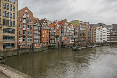 Buildings by river against sky in city