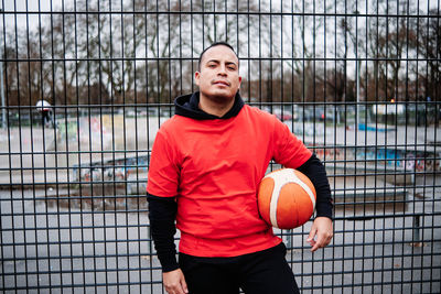 Man holding ball while standing by fence