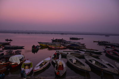 Boats moored in sea against sky during sunset