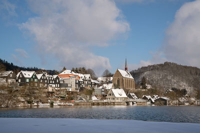 Houses by river and buildings against sky