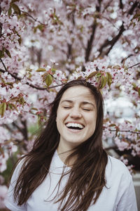 Smiling young woman standing against pink tree