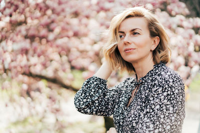 Beautiful woman looking away against cherry tree