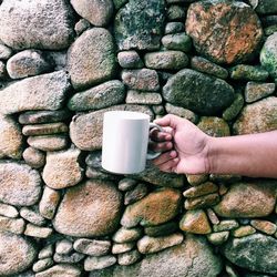 Midsection of man holding coffee cup against wall