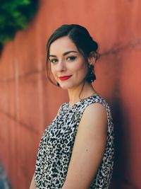 Portrait of young woman standing against wall