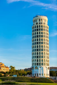 Tall building in city against blue sky