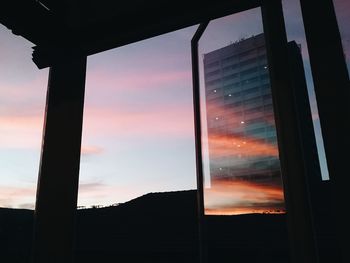 Silhouette of building against cloudy sky at sunset