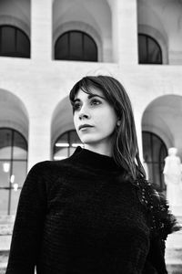 Portrait of young woman standing against built structure