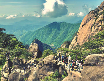Panoramic view of tourists on mountain against cloudy sky