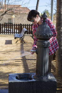 Woman in sunglass washing hands from water fountain