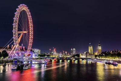 Illuminated ferris wheel in city at night