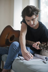 Young musician writing songs on an acoustic guitar