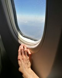 Cropped hand on airplane window