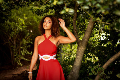 Portrait of young woman standing against tree