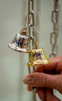 Close-up of hand holding chain by bells with text