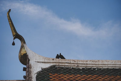 Low angle view of horse sculpture on roof against sky