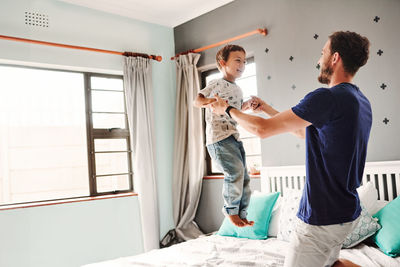 Father with son playing on bed at home