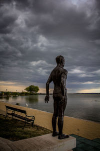 Statue by sea against sky