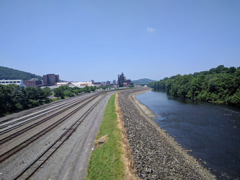 Road by river in city against clear blue sky