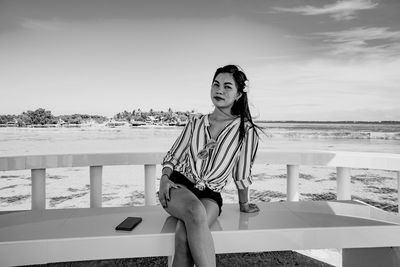 Portrait of woman standing at beach against sky