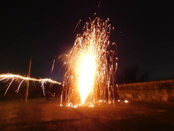 Firework display on field against sky at night