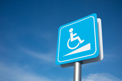 Low angle view of information sign against blue sky