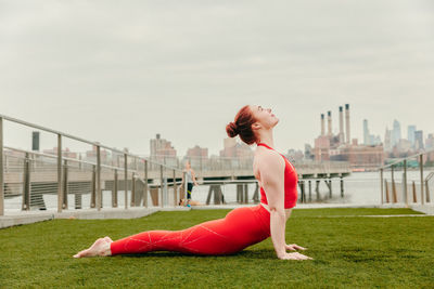 Young female athlete stretching by waterfront in brooklyn.