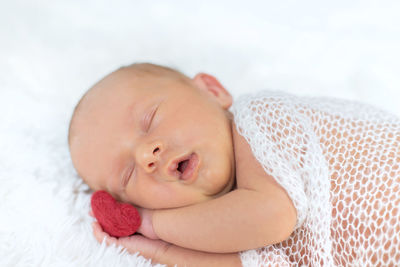 Close-up of cute baby boy lying on bed at home