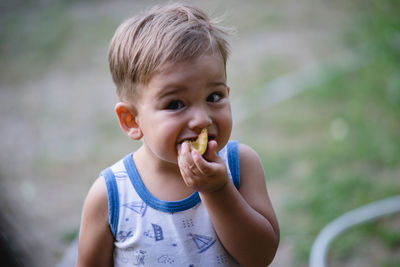 Portrait of cute boy eating food while standing at backyard