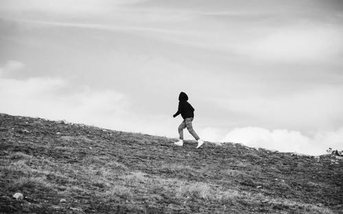 Man running on field against cloudy sky