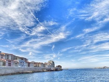 Buildings by sea against blue sky