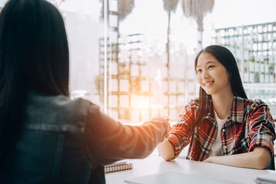 Portrait of a smiling young woman sitting on table