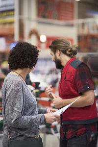 Side view of salesman and customer standing in hardware store
