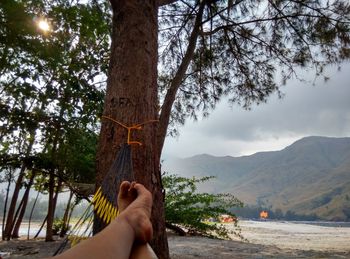 Low section of person in hammock against sky