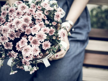 Midsection of woman holding pink flowers bouquet