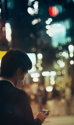 Midsection of man using mobile phone at night