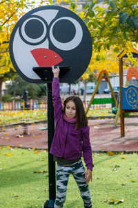 Girl with arm raised standing in park