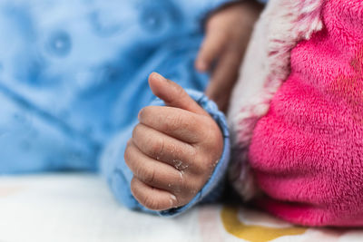 Cropped unrecognizable newborn baby lying on big toy on cozy blanket