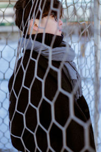 Side view of handsome young man standing by net during winter