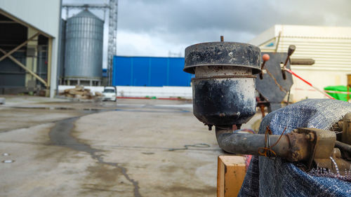 Man working on metal in city against sky