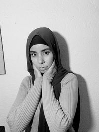 Portrait of young woman standing against wall